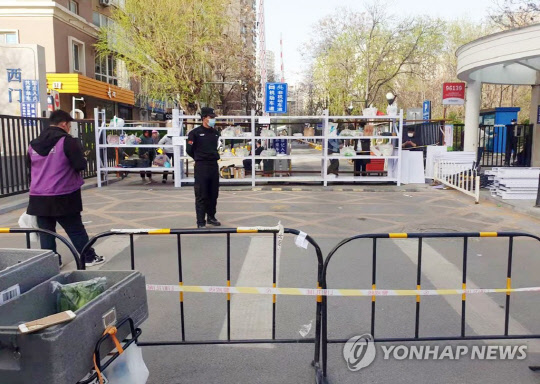 5일 오후 중국 베이징 차오양구 한인 밀집지역인 왕징에서 코로나19 확진자가 발생한 가운데 왕징의 한 봉쇄된 아파트 입구에서 주민들과 배달원들이 식료품을 주고 받고 있다. <연합뉴스>
